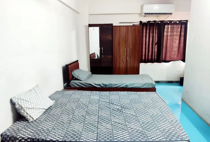 Room with a large bed and a single bed, blue floor, wardrobe and wall AC